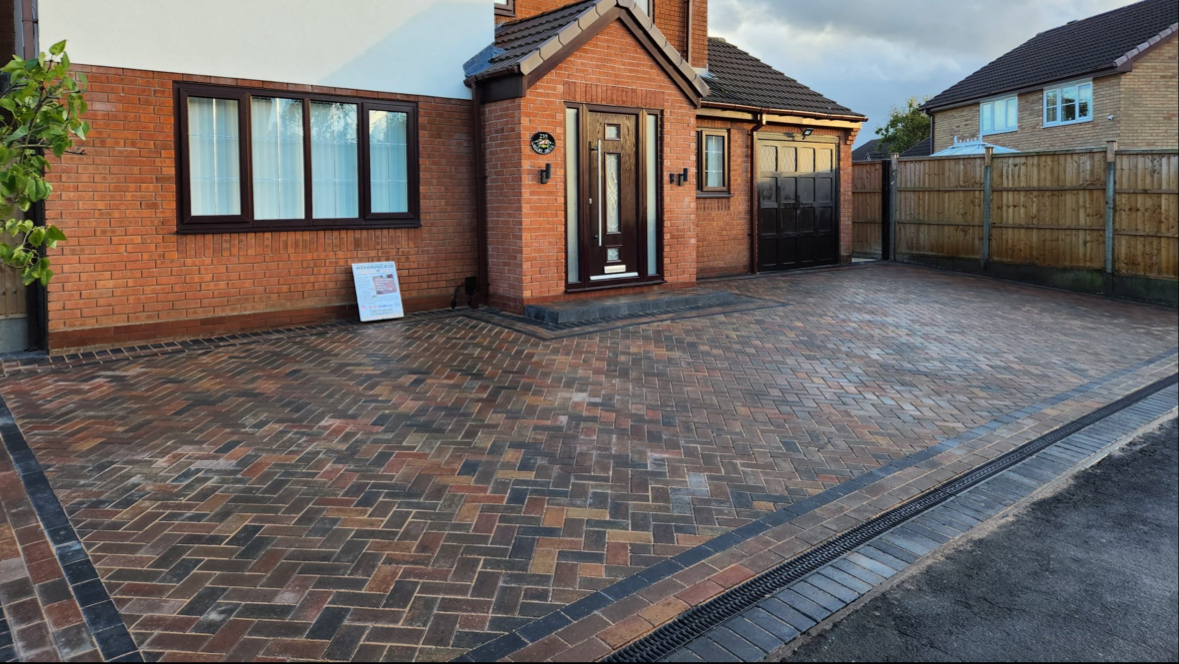 Herringbone block-paved driveway in brindle tones with a charcoal border and drainage channel