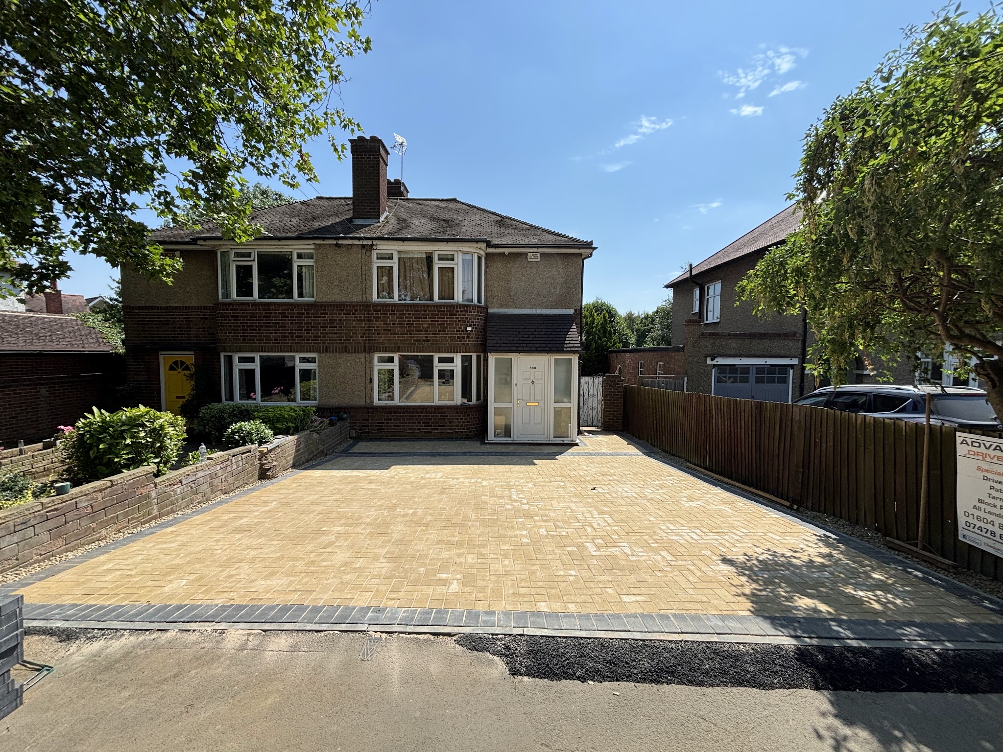 Buff block-paved driveway leading to a semi-detached house with a low brick wall